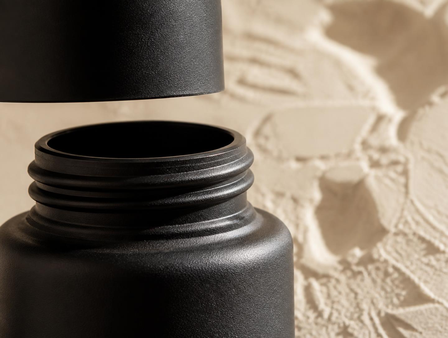Macro detail of a matte black cosmetic bottle neck and cap