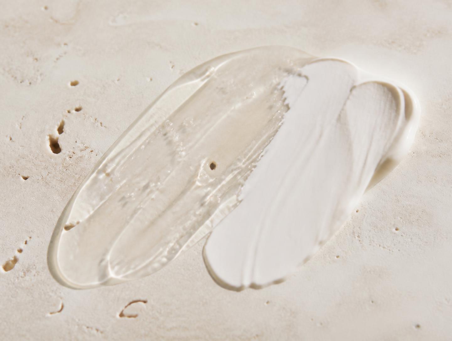 Clear gel and cream textures swatched on warm ivory stone